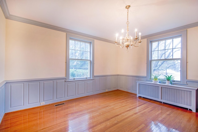 empty room featuring radiator heating unit, an inviting chandelier, and crown molding
