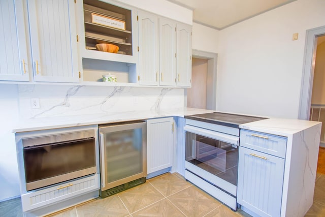 kitchen with light stone counters, white electric stove, tasteful backsplash, a peninsula, and beverage cooler
