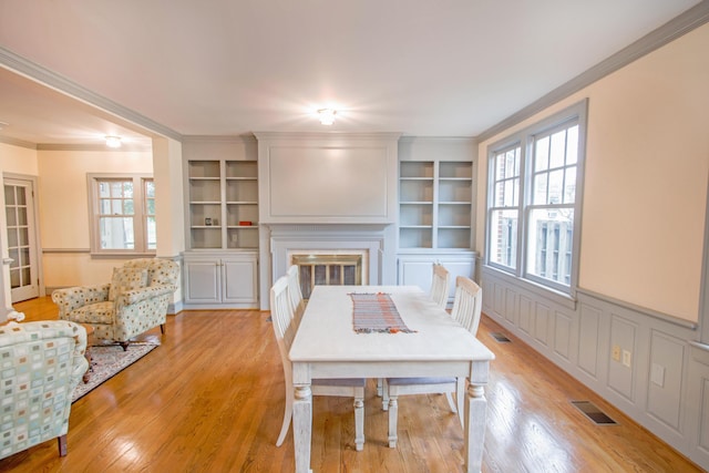 dining room with a glass covered fireplace, a healthy amount of sunlight, and light wood finished floors