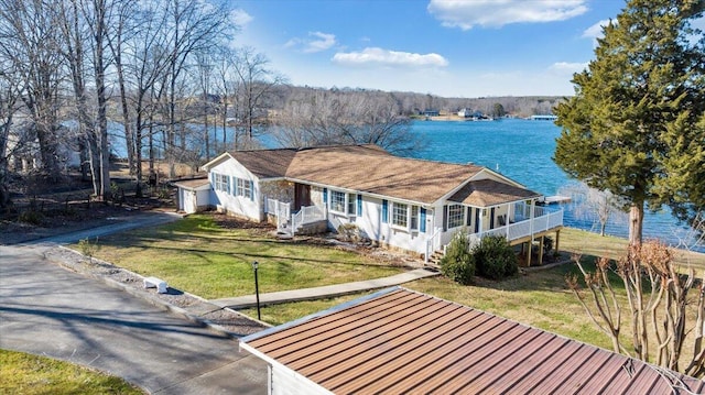view of front of house featuring a front yard, covered porch, an outbuilding, a water view, and a garage