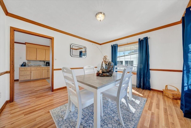 dining room featuring baseboards, crown molding, and light wood-style floors
