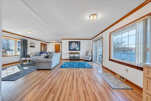 unfurnished living room with light wood finished floors, visible vents, crown molding, and a textured ceiling