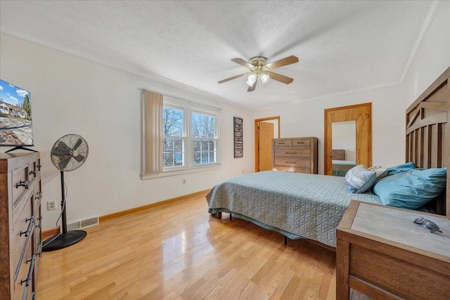 bedroom featuring ornamental molding, a textured ceiling, baseboards, and light wood-type flooring