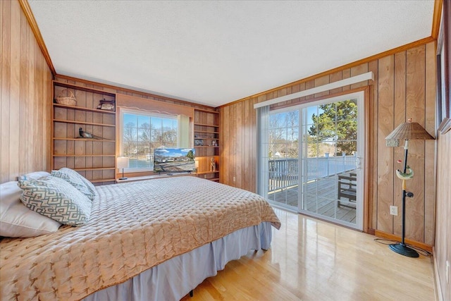bedroom with multiple windows, a textured ceiling, wooden walls, and access to exterior