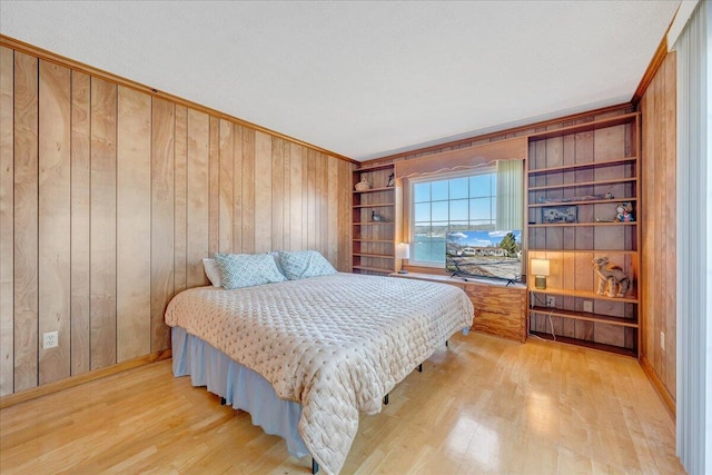 bedroom featuring ornamental molding, wooden walls, and light wood-type flooring