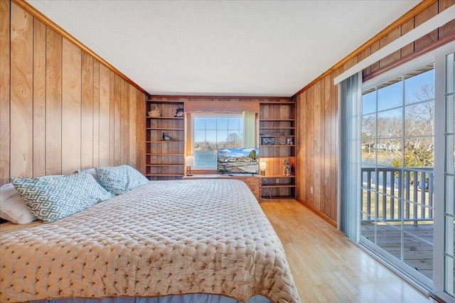 bedroom featuring access to exterior, wood finished floors, wood walls, and ornamental molding