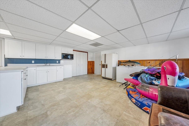 below grade area featuring light floors, a sink, and a paneled ceiling