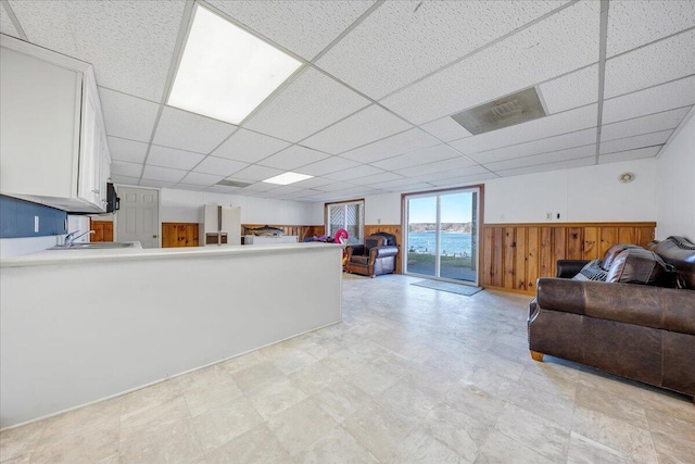 living area with a wainscoted wall, wood walls, and a paneled ceiling