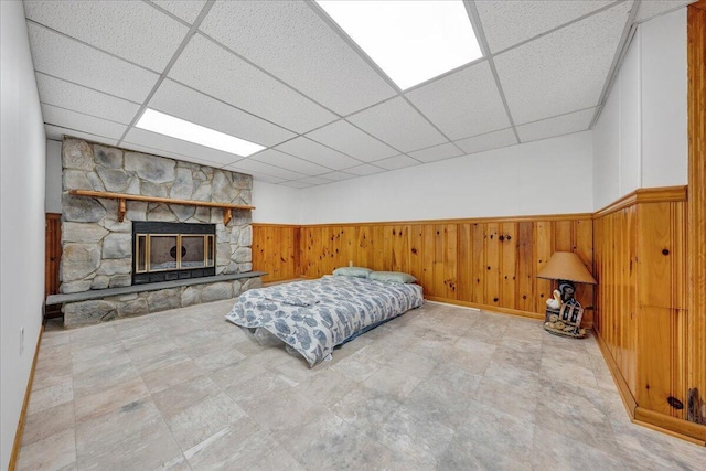 bedroom with a drop ceiling, wood walls, and wainscoting