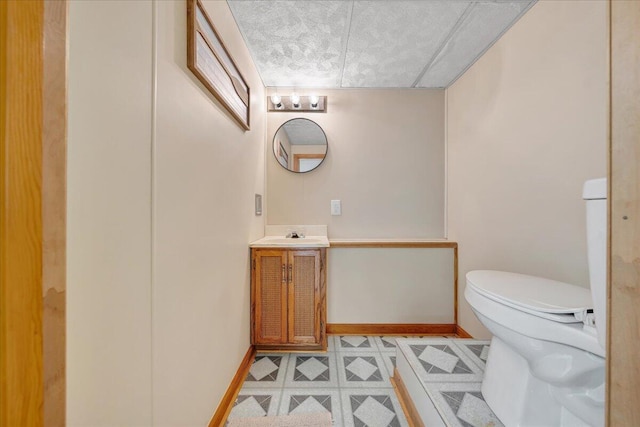 bathroom with baseboards, toilet, tile patterned floors, and vanity