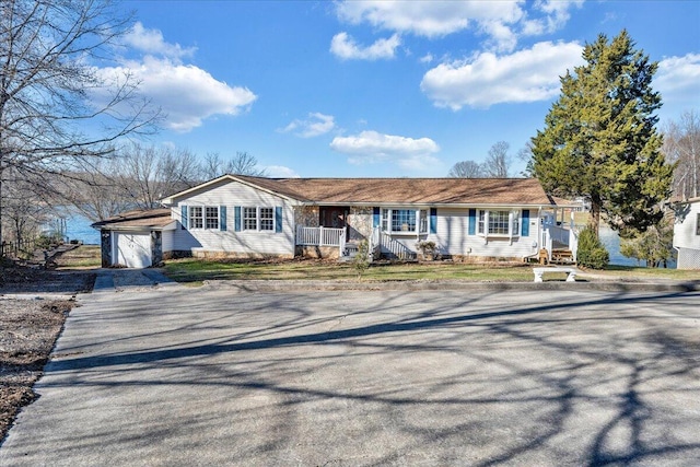 ranch-style house with an outdoor structure, a porch, driveway, and an attached garage