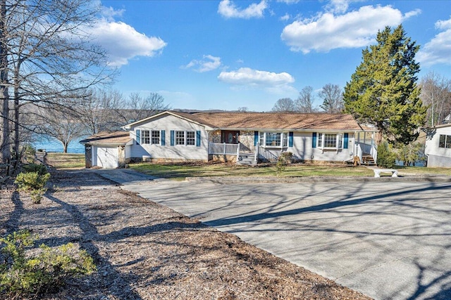 ranch-style home with covered porch, an outbuilding, driveway, and a garage