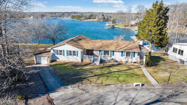 view of front of house featuring a water view, a garage, a front lawn, driveway, and an outbuilding