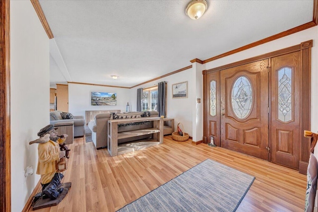 foyer with baseboards, crown molding, light wood-style floors, and a textured ceiling