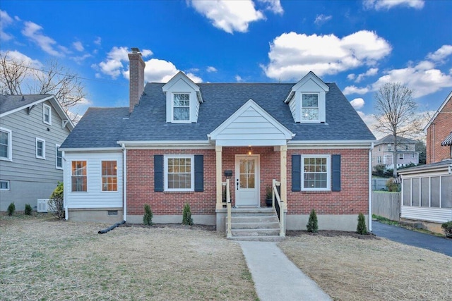 cape cod house with brick siding, a shingled roof, and a chimney