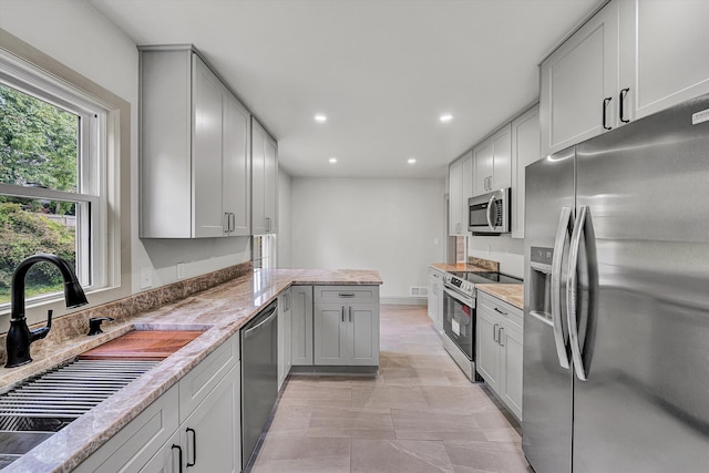2619 Carolina Ave SW, Roanoke, VA 24014 - kitchen featuring appliances with stainless steel finishes, a sink, a peninsula, recessed lighting, and light stone countertops