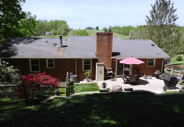 back of house featuring a chimney, fence, a patio, and a lawn