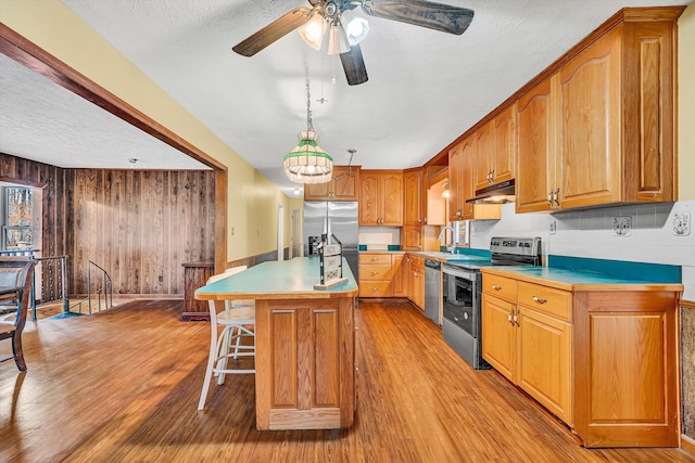 kitchen featuring light wood-type flooring, light countertops, under cabinet range hood, and appliances with stainless steel finishes