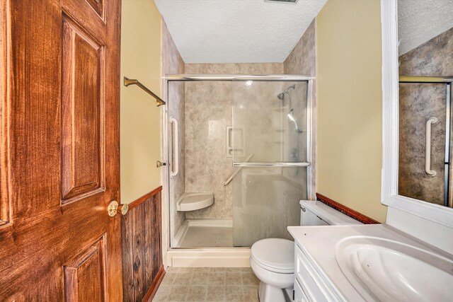 bathroom featuring a textured ceiling, toilet, a stall shower, and vanity