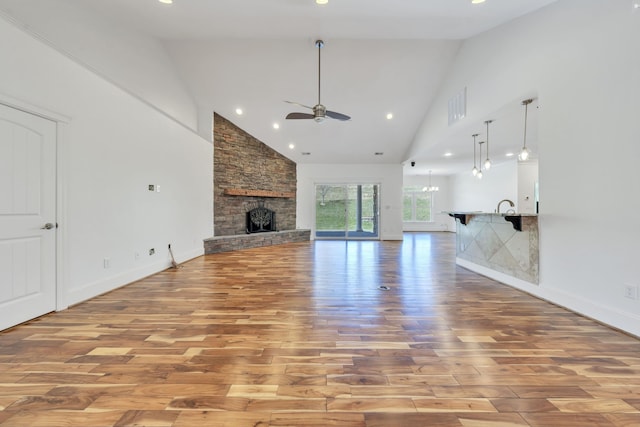 7425 Willow Leaf Cir, Roanoke, VA 24018 - unfurnished living room with high vaulted ceiling, wood finished floors, a ceiling fan, a stone fireplace, and baseboards