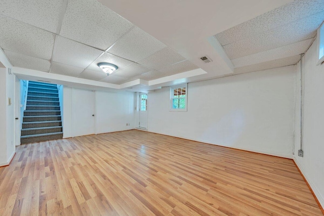 basement with stairs, visible vents, a drop ceiling, and light wood-style floors