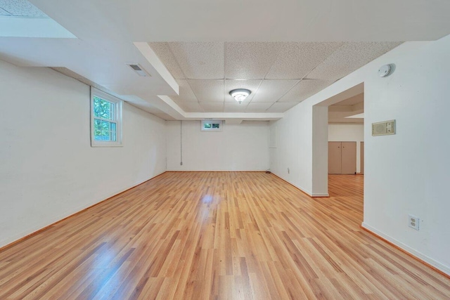 unfurnished room featuring a paneled ceiling, visible vents, light wood-style flooring, and baseboards