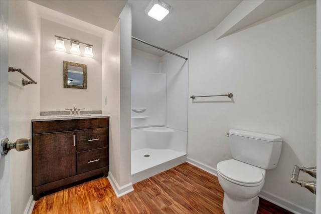 full bath featuring vanity, toilet, a shower, baseboards, and wood finished floors