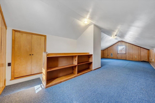 additional living space with lofted ceiling, wood walls, and carpet flooring