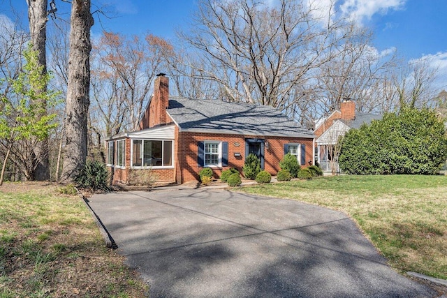ranch-style house featuring a chimney, a front yard, and brick siding