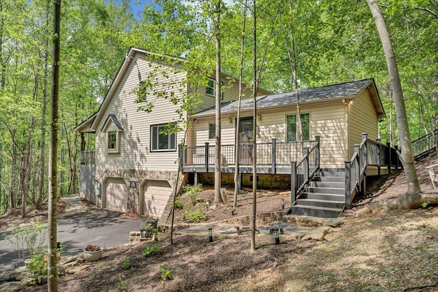 view of front of property featuring stairs, driveway, an attached garage, and a deck