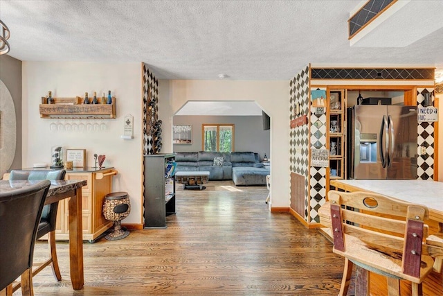 interior space featuring arched walkways, a textured ceiling, and wood finished floors