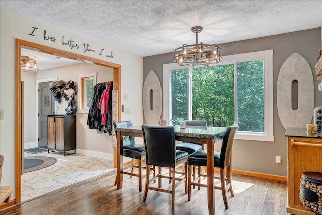 dining space featuring baseboards, light wood-style flooring, a chandelier, and a healthy amount of sunlight