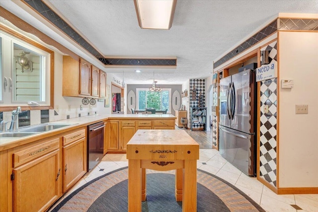 kitchen with a textured ceiling, appliances with stainless steel finishes, a sink, light countertops, and a peninsula