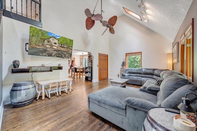 living room featuring high vaulted ceiling, track lighting, wood finished floors, and ceiling fan with notable chandelier