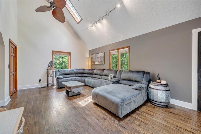 living room with track lighting, a ceiling fan, wood finished floors, and a healthy amount of sunlight