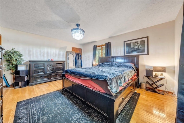 bedroom featuring an inviting chandelier, a textured ceiling, and wood finished floors