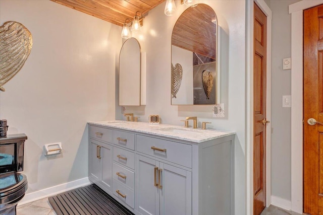 bathroom featuring double vanity, baseboards, wood ceiling, and a sink