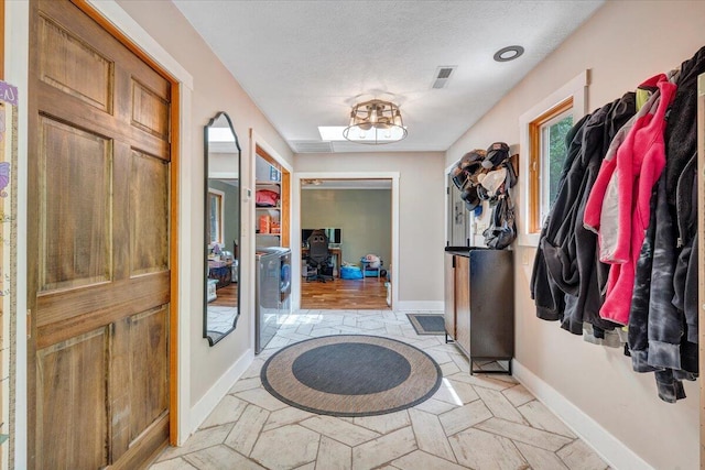 entrance foyer featuring baseboards, a textured ceiling, washer / clothes dryer, and visible vents