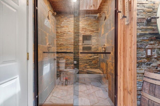 bathroom with stone finish flooring, a stall shower, and toilet
