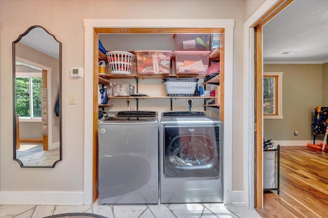 laundry area featuring washing machine and clothes dryer, baseboards, ornamental molding, and laundry area