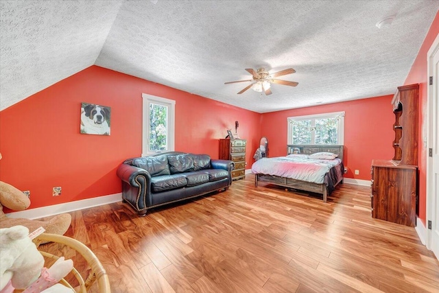 bedroom featuring ceiling fan, a textured ceiling, vaulted ceiling, wood finished floors, and baseboards