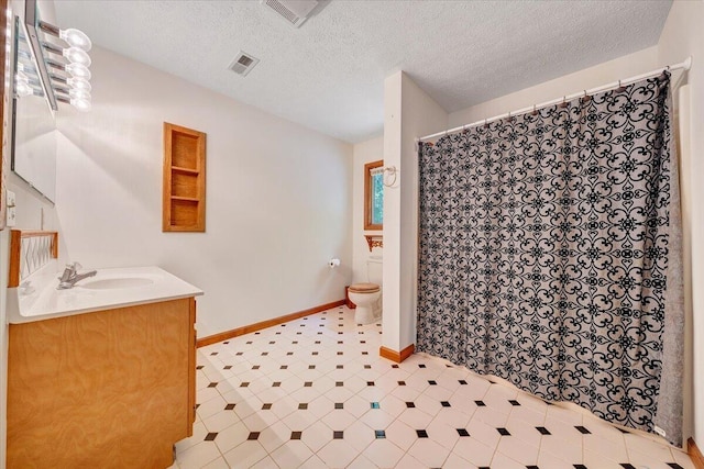 full bathroom featuring a textured ceiling, visible vents, vanity, baseboards, and toilet