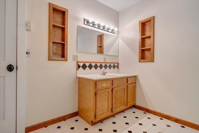 bathroom with vanity, decorative backsplash, baseboards, and tile patterned flooring
