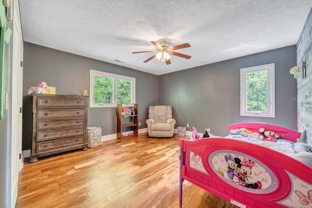 bedroom featuring visible vents, a textured ceiling, wood finished floors, and multiple windows