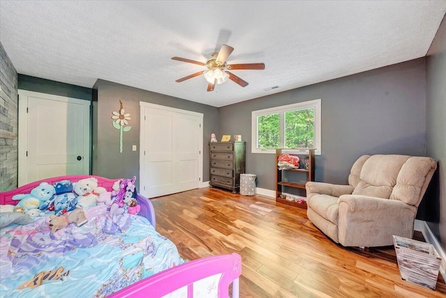 bedroom with light wood-style floors, ceiling fan, a textured ceiling, and visible vents