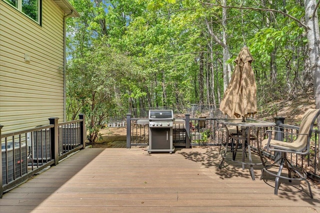 deck with outdoor dining area, fence, and area for grilling