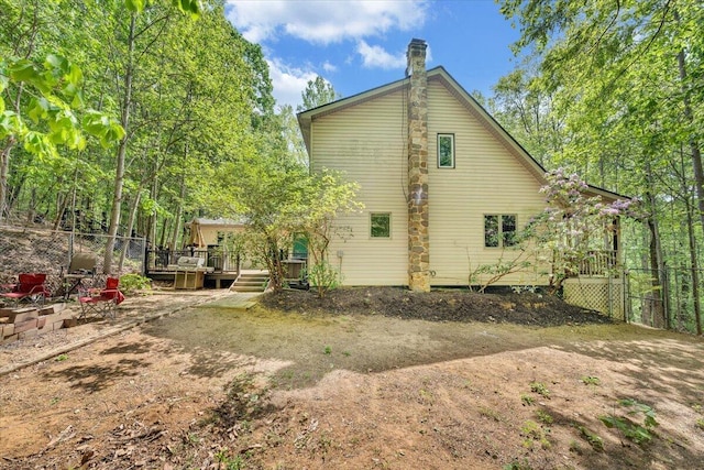 back of house with fence, a wooden deck, and a chimney