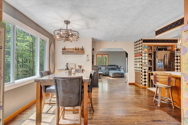 dining room with a healthy amount of sunlight, baseboards, a textured ceiling, and wood finished floors