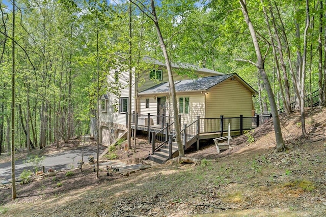 exterior space with stairway, a wooden deck, and roof with shingles