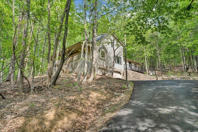 view of side of home with a garage, a view of trees, and driveway